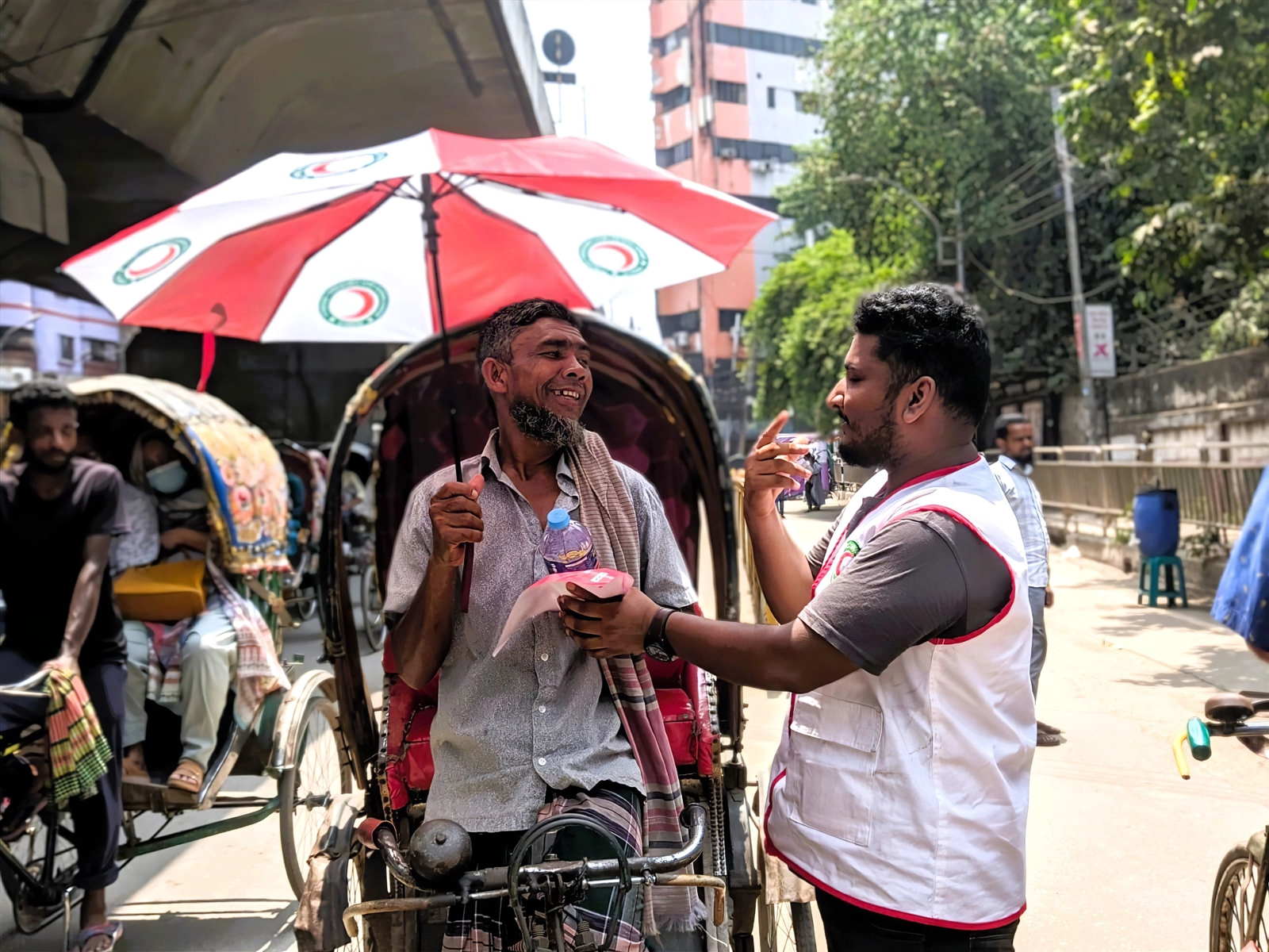 | Image: Drinking water and umbrellas distributed among rickshaw pullers in Dhaka.