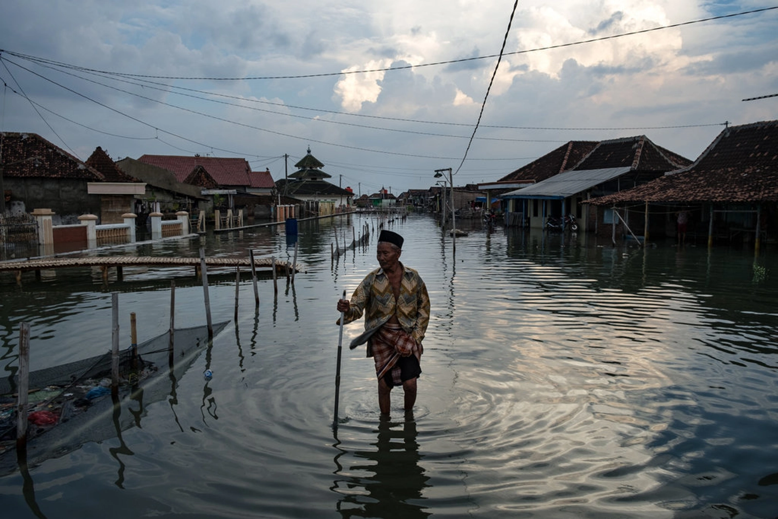 A resident slowly makes his way through the inundated streets of the village due to rising sea levels. Sayung subdistrict, Demak, Central Java, Indonesia.